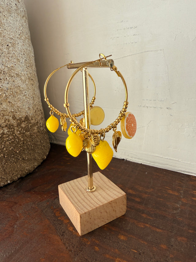 Argolas douradas com pendentes de limão e laranja, frescas e coloridas, perfeitas para looks vibrantes.
