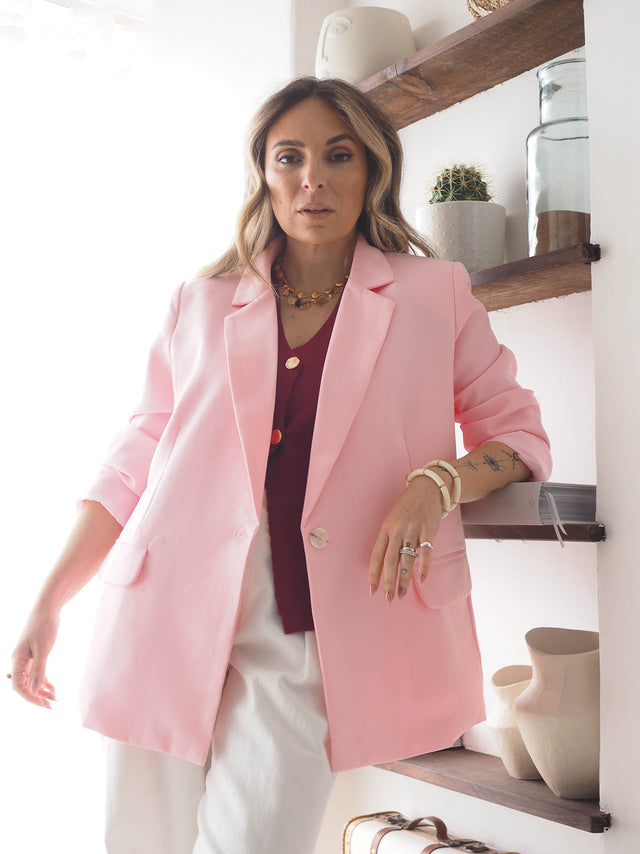Modelo usando blazer rosa básico de corte reto, com gola em lapela e bolsos, destacando elegância moderna.