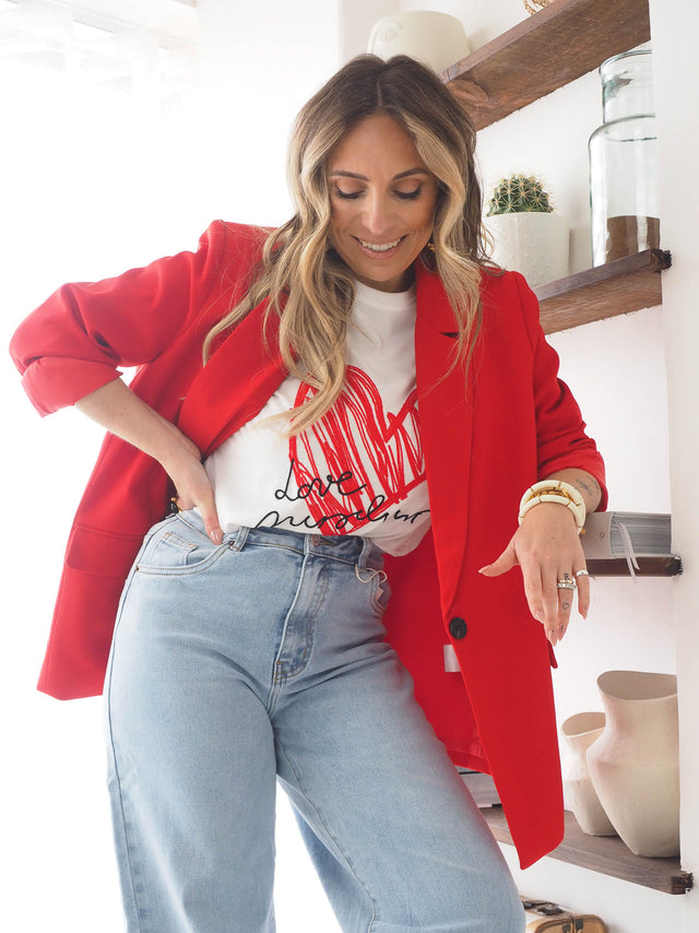 Woman in a red blazer and graphic t-shirt, showcasing modern sophistication and stylish comfort.