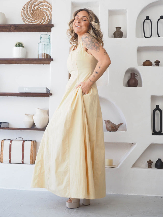 Modelo usando vestido comprido de alças em tom amarelo, destacando elegância e conforto em ambiente moderno.