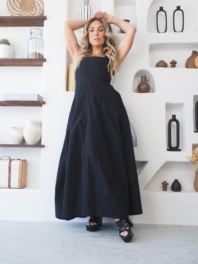 Modelo usando vestido comprido de alças preto, com fecho invisível e corte cintado para um look elegante.