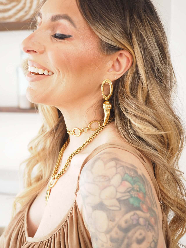 Brincos com Corno Banhados a Ouro em mulher, destacando elegância e estilo moderno.