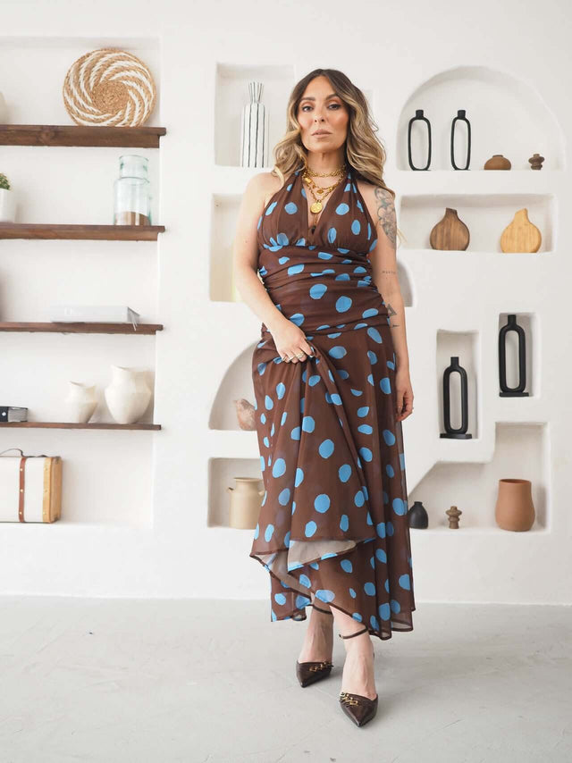 Modelo usando um Vestido Halter Bolas em tons de marrom e azul, com decote que valoriza os ombros.