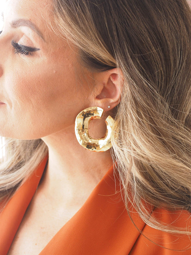 Brincos circulares martelados dourados, acessórios modernos e sofisticados, perfeitos para looks versáteis.