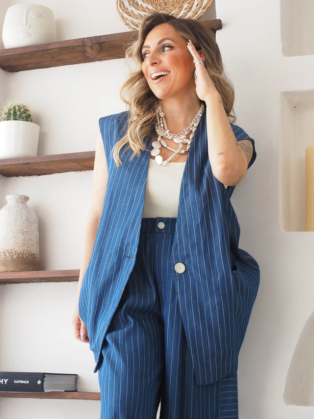 Mulher com colete riscas oversized azul, look casual e moderno, confeccionado em algodão, estilo clássico.