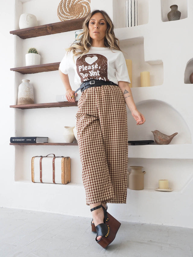 Mulher a usar calças xadrez com cintura alta e blusa divertida, destacando estilo moderno e casual.