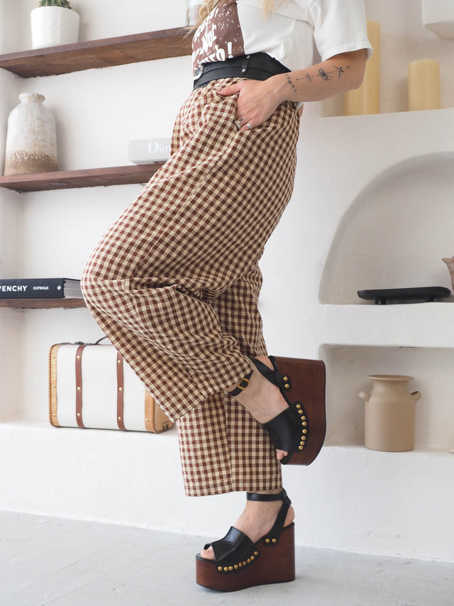 Calças xadrez em tons castanho com cintura alta, oferecendo estilo e conforto, perfeitas para looks casuais.