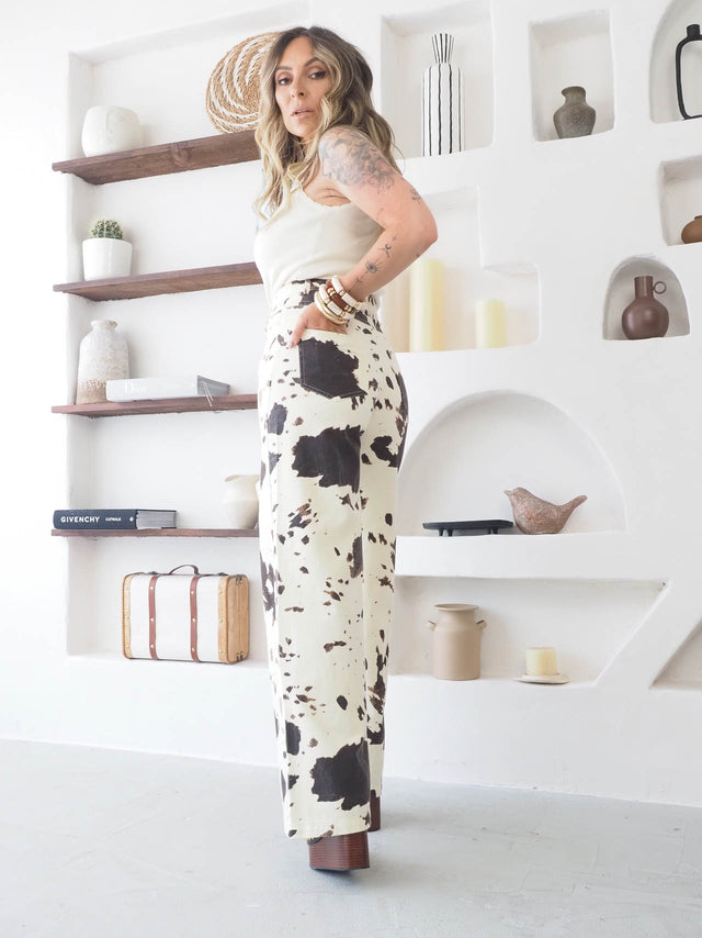 Mulher a usar calças de ganga estampado vaca em ambiente moderno e descontraído, ideal para o verão.