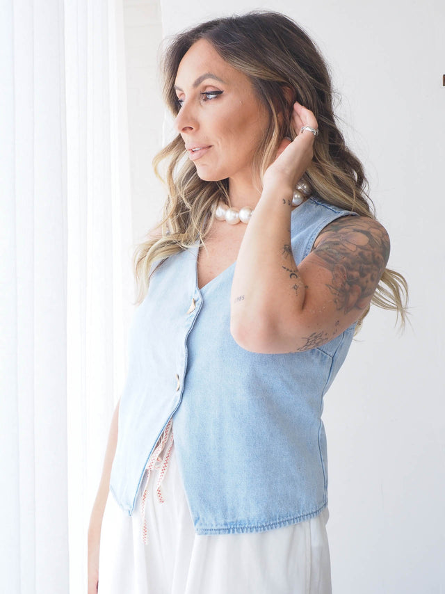 Mulher a usar colete de ganga cintado com decote em bico, ideal para looks casuais e elegantes no verão.