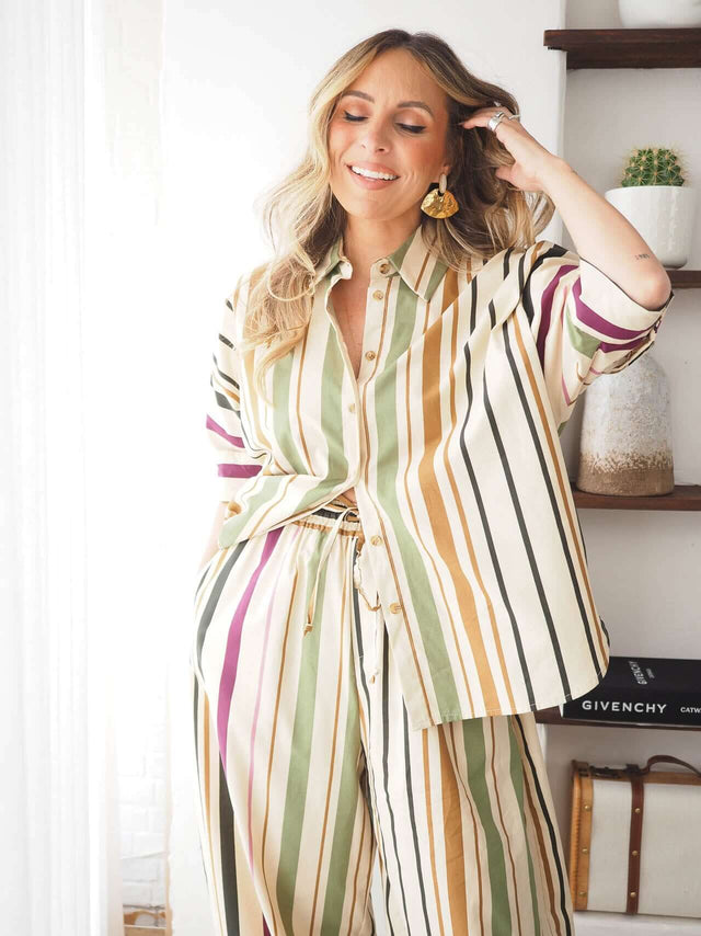 Camisa às Riscas oversized em linho com padrão riscas em cores variadas, usada com calças também às riscas.
