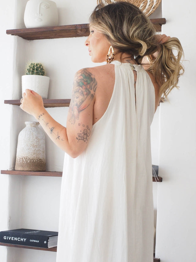 Modelo com vestido halter comprido em algodão, destacando decote e abertura nas costas. Ideal para verão.