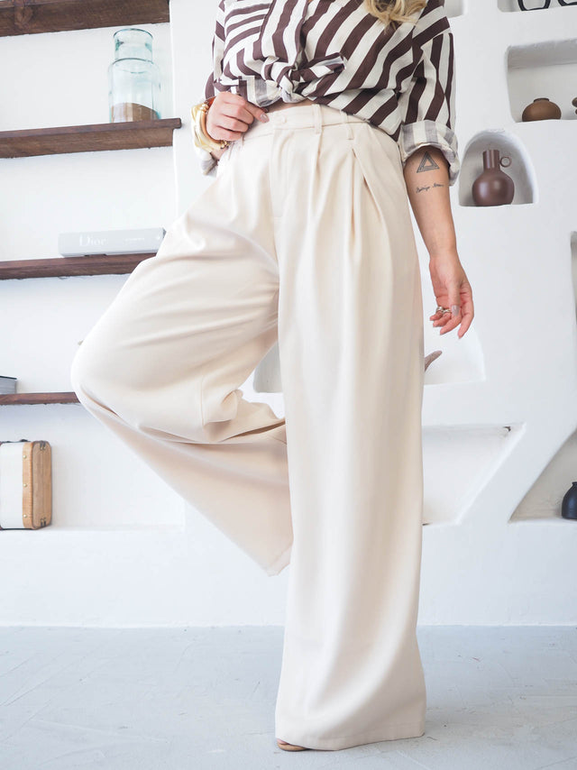 Calças com pregas em tons claros, com cintura alta, proporcionando um look sofisticado e confortável.