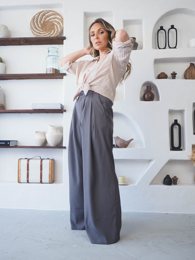 Modelo em calças com pregas cinzentas, camisa clara, destacando elegância e conforto moderno.