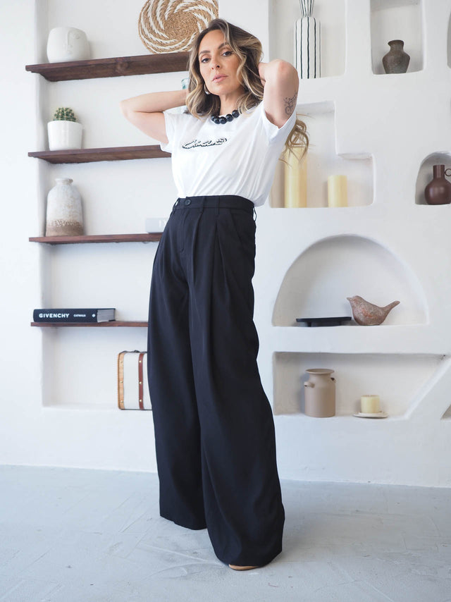 Modelo elegante com calças de cintura alta e pregas frontais, combinando sofisticação e conforto moderno.
