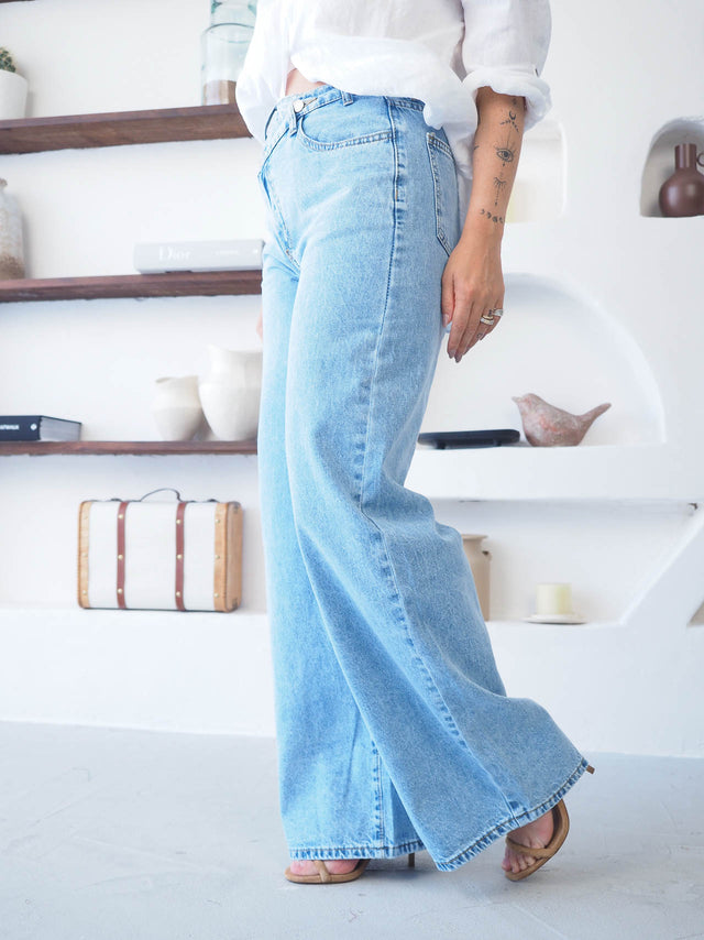 Calças de ganga wide leg com cintura cruzada, oferecendo conforto e estilo moderno, perfectas para qualquer ocasião.