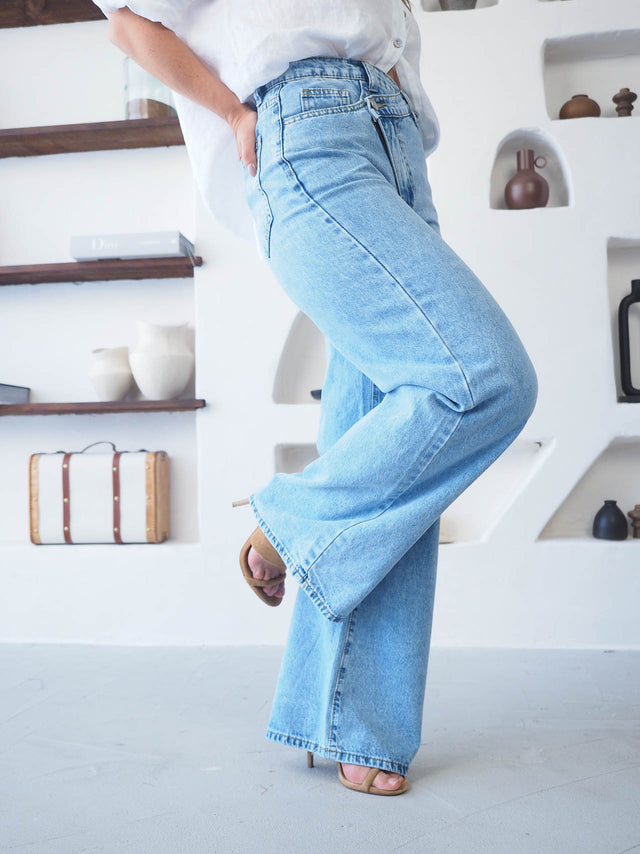 Calças de ganga wide leg com cintura cruzada em azul claro, perfeita para um look moderno e confortável.
