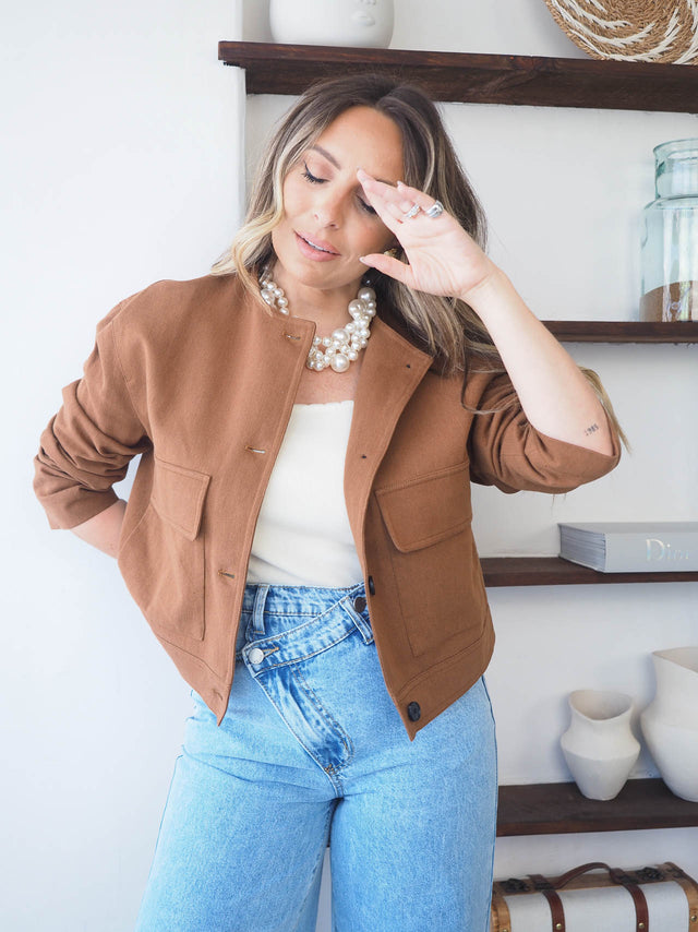 Blusão curto com botões em tom terra, ideal para looks casuais e formais, com um toque de elegância.