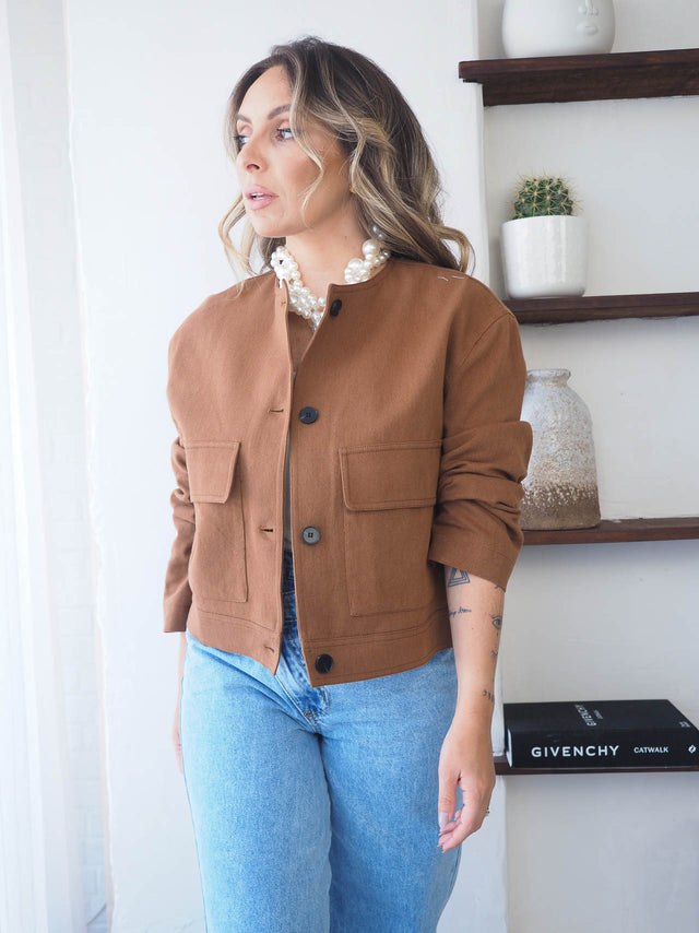 Blusão curto com botões em tom castanho, ideal para looks elegantes e casuais-chic.