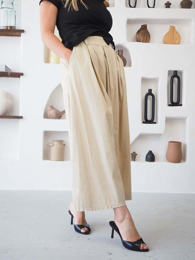 Calças Culote em algodão, cor bege, com pregas frontais e ajuste na cintura para um look confortável e elegante.