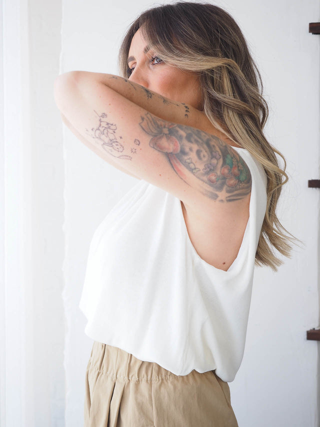 Top de malha leve e fresco em cor branca, ideal para combinações com calças femininas e blazers elegantes.