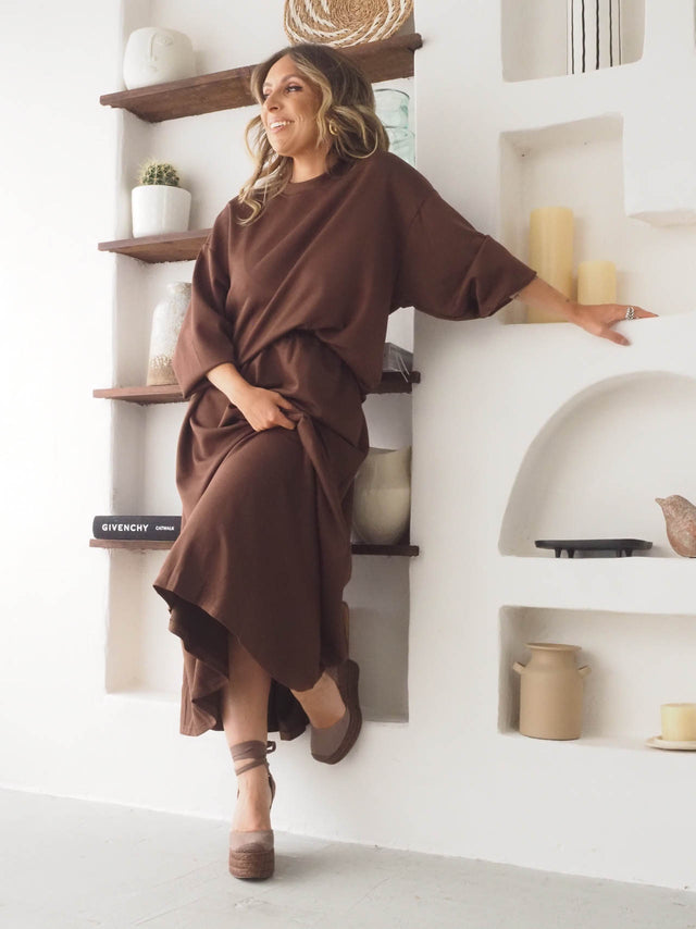 Conjunto de felpa feminina em tom castanho, destacando a sweatshirt e saia moderna, ideal para um visual confortável.