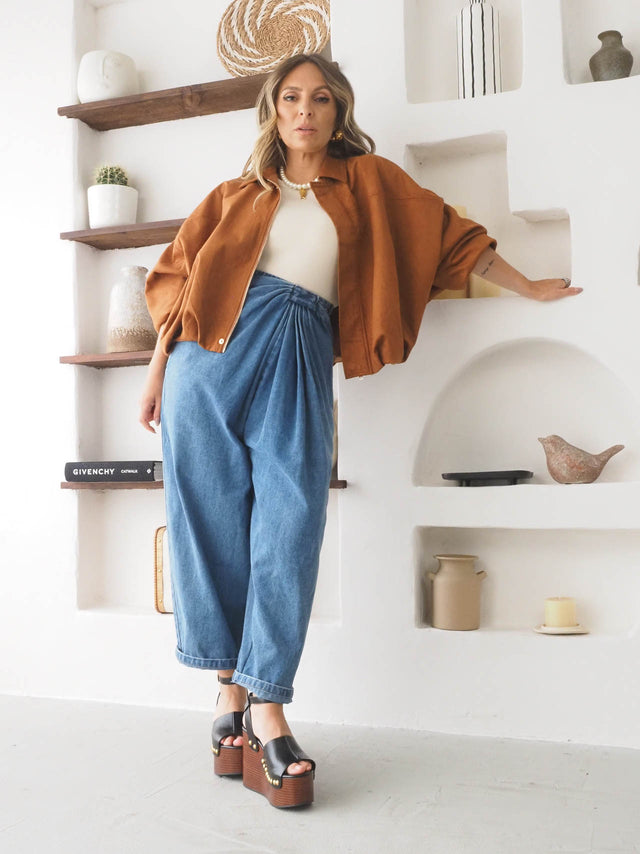 Mulher usando calças baggy com drapeado e blazer oversize laranja, estilo descontraído e moderno.