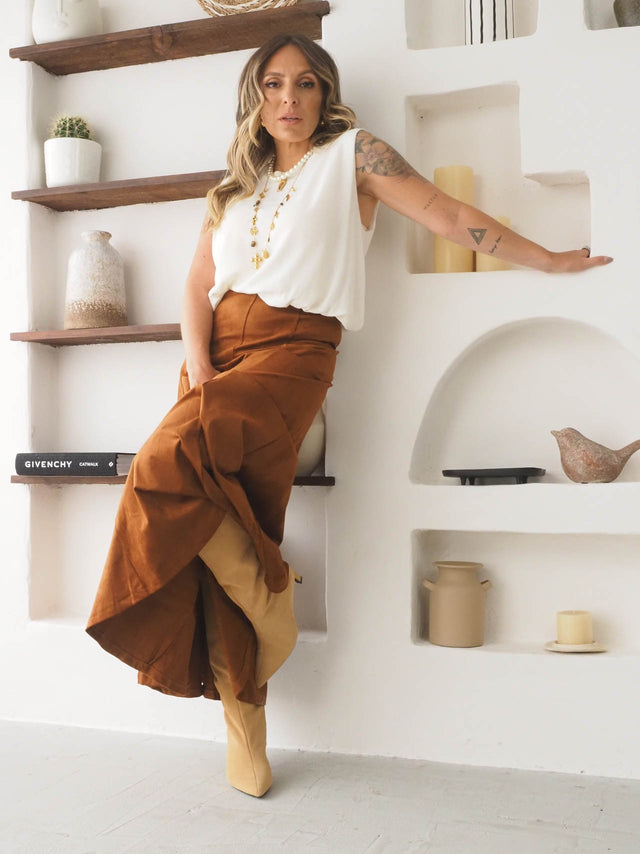 Saia midi efeito camurça em look casual, combinado com blusa feminina e botas, num ambiente moderno e estiloso.