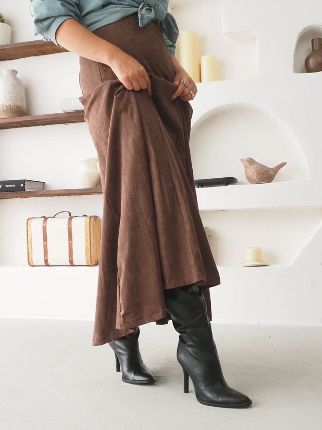 Saia midi efeito camurça em tom castanho, combinada com botas pretas, ideal para um look casual e elegante.