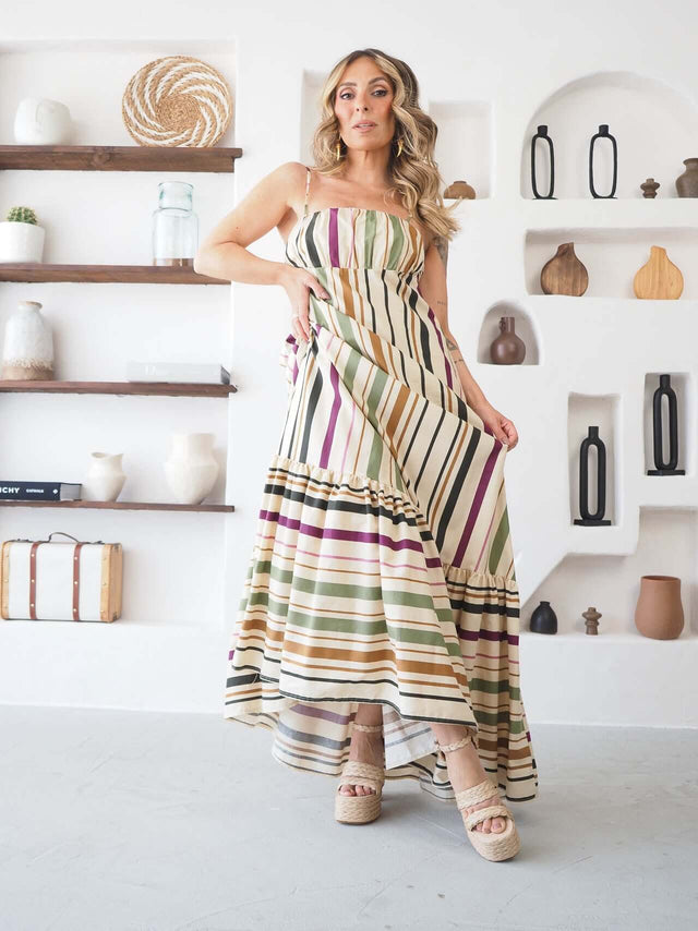 Vestido longo às riscas multicolor, alças finas, com a modelo a segurar a saia a mostrar o caimento fluido.