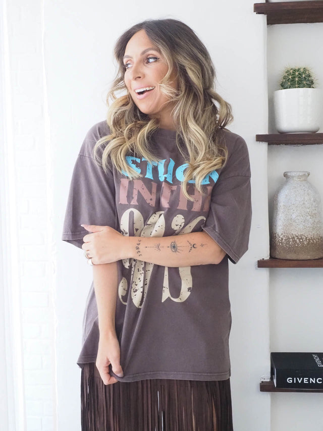 T-shirt 90's de manga curta com estampa vintage, combinada com saia midi de franjas, estilo descontraído e moderno.