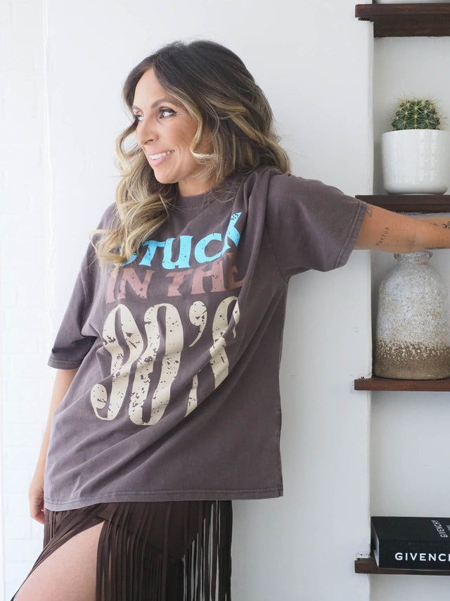 T-shirt feminina dos anos 90 em tom castanho, estilo vintage, combinada com saia franjada, perfeita para looks descontraídos.