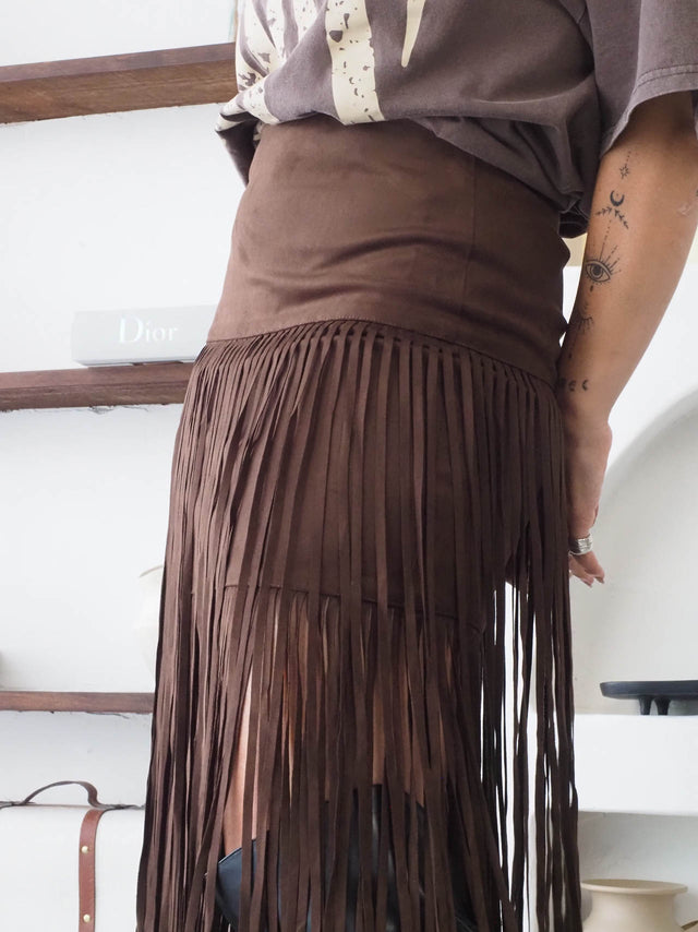 Saia com franjas em camurça castanha, estilo boho-chic, ideal para looks modernos e confortáveis.