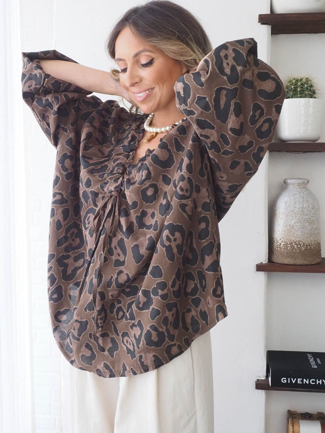 Blusa com drapeado animal print, manga larga e decote em bico, ideal para looks elegantes e versáteis na primavera-verão.