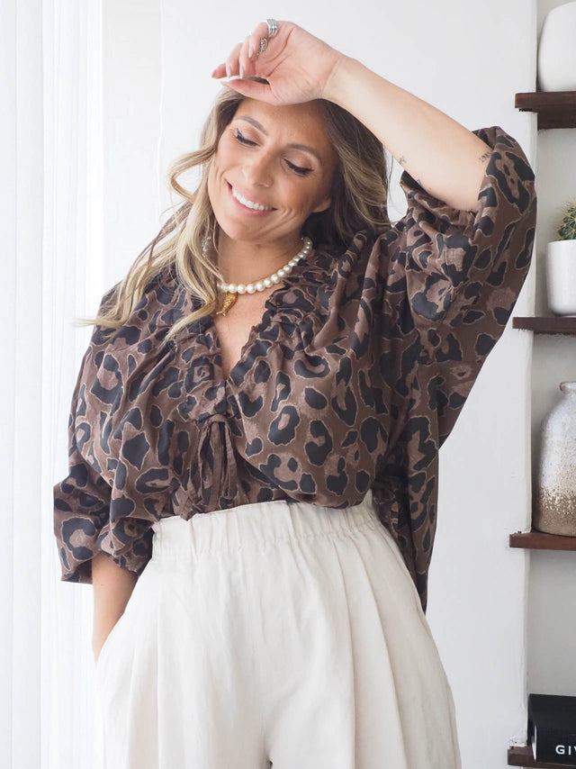 Blusa com drapeado animal print, ideal para blusas femininas elegantes, combinada com calças largas.