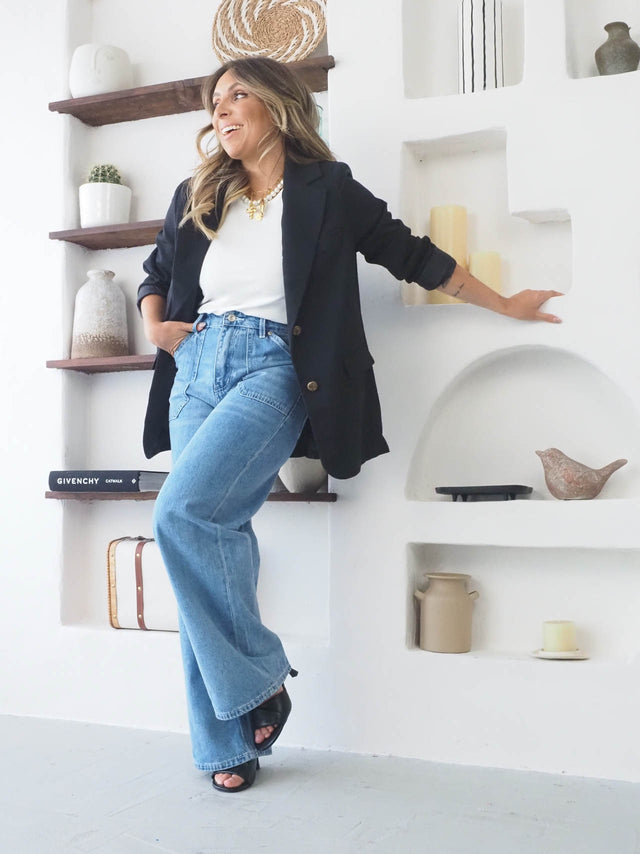 Mulher sorridente vestindo blazer feminino oversize com calça wide leg, destacando estilo moderno e elegante.