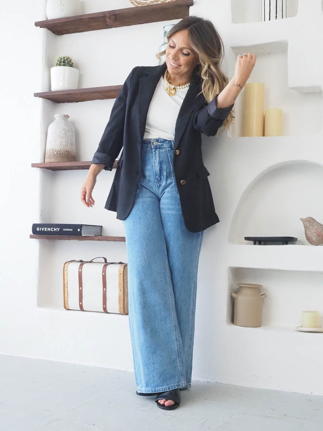 Modelo feminina com blazer preto oversized, t-shirt e jeans cintura alta, destacando um look elegante e casual.