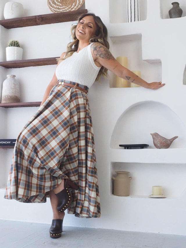 Mulher sorridente a usar a saia midi xadrez com padrão vintage, mostrando estilo e conforto no dia a dia.