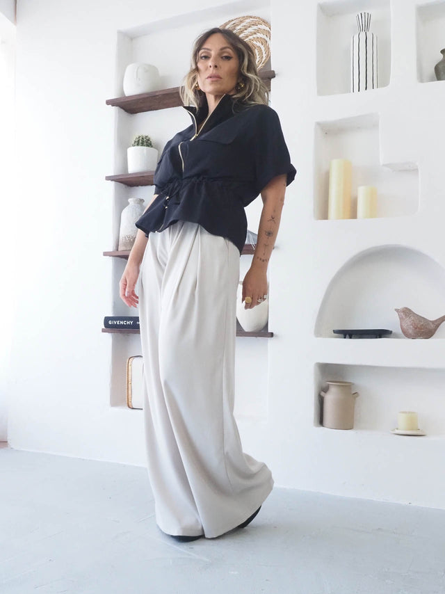 Camisa Safari Com Cordão usada por mulher com calças largas em ambiente moderno.