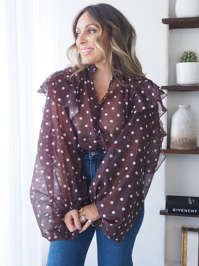 Modelo a usar blusa com bolas em tons marrons com folhos, estilo elegante e romântico.