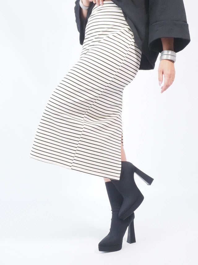 A abertura na parte de baixo da saia midi adiciona um toque de fluidez e movimento ao look.