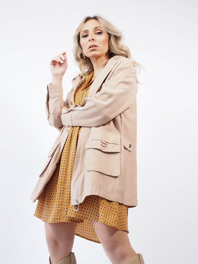 Vestido com decote em bico combinado com uma parka bege.
