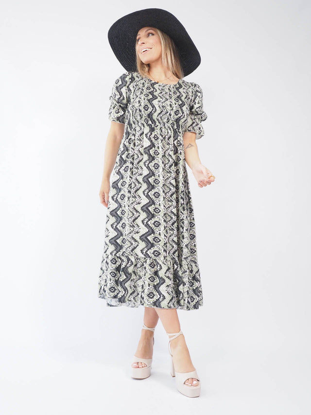 Vestido midi estampado combinado com chapéu de aba larga.