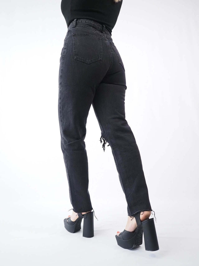 Calças de ganga rotas mom fit de mulher e de bainha desfeitas, street style.