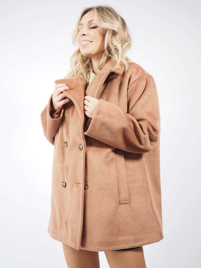 Casaco sobretudo camel, combinado com uma camisola de malha e calções.