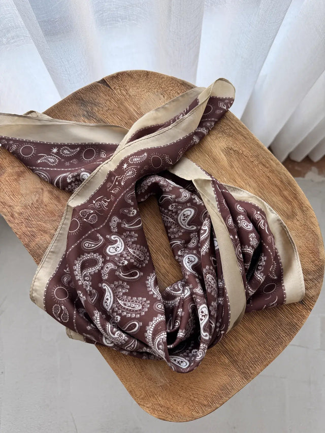 Lenço Quadrado Estampado castanho com padrão paisley sobre fundo claro.