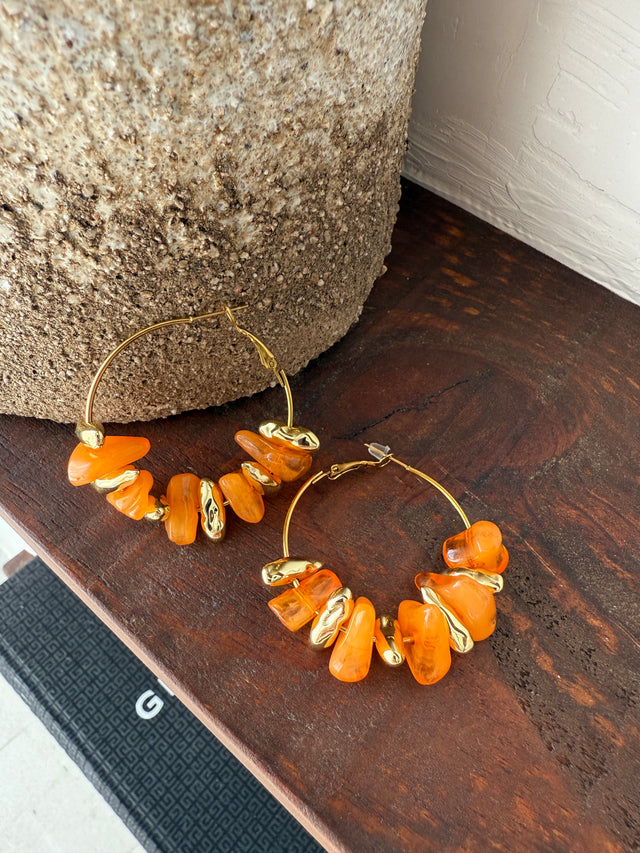 Argolas com pedras laranjas e douradas, acessórios vibrantes para dar vida ao seu look.