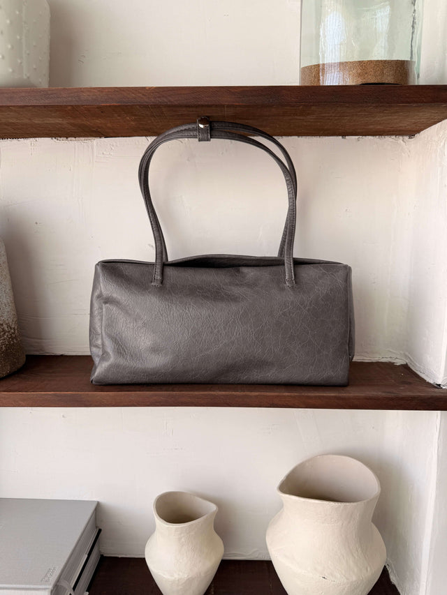 Tote Bag Ecopele cinzenta exposta em prateleira de madeira