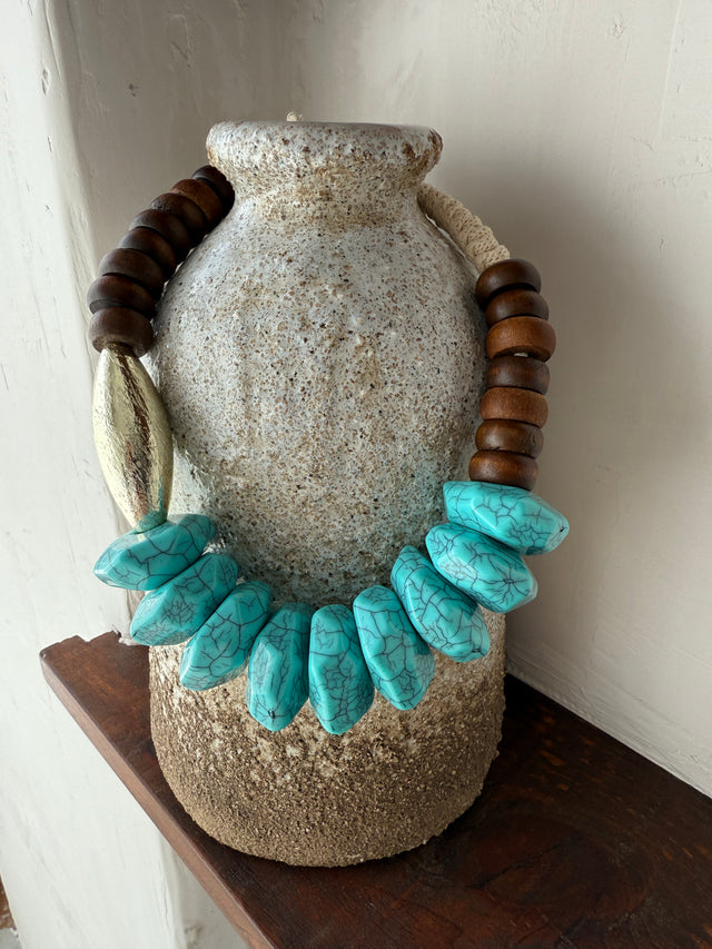 Colar em corda com pedras turquesa e detalhes em madeira, destacando a beleza natural e o design contemporâneo.