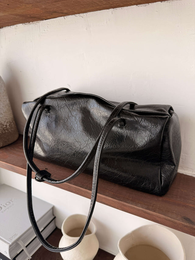 Tote Bag Ecopele preta com alça longa sobre prateleira de madeira