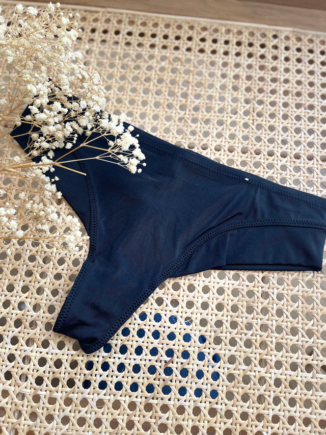 Cueca Asa Delta preta em microfibra, conforto e sensualidade com detalhe de flores secas em fundo natural.